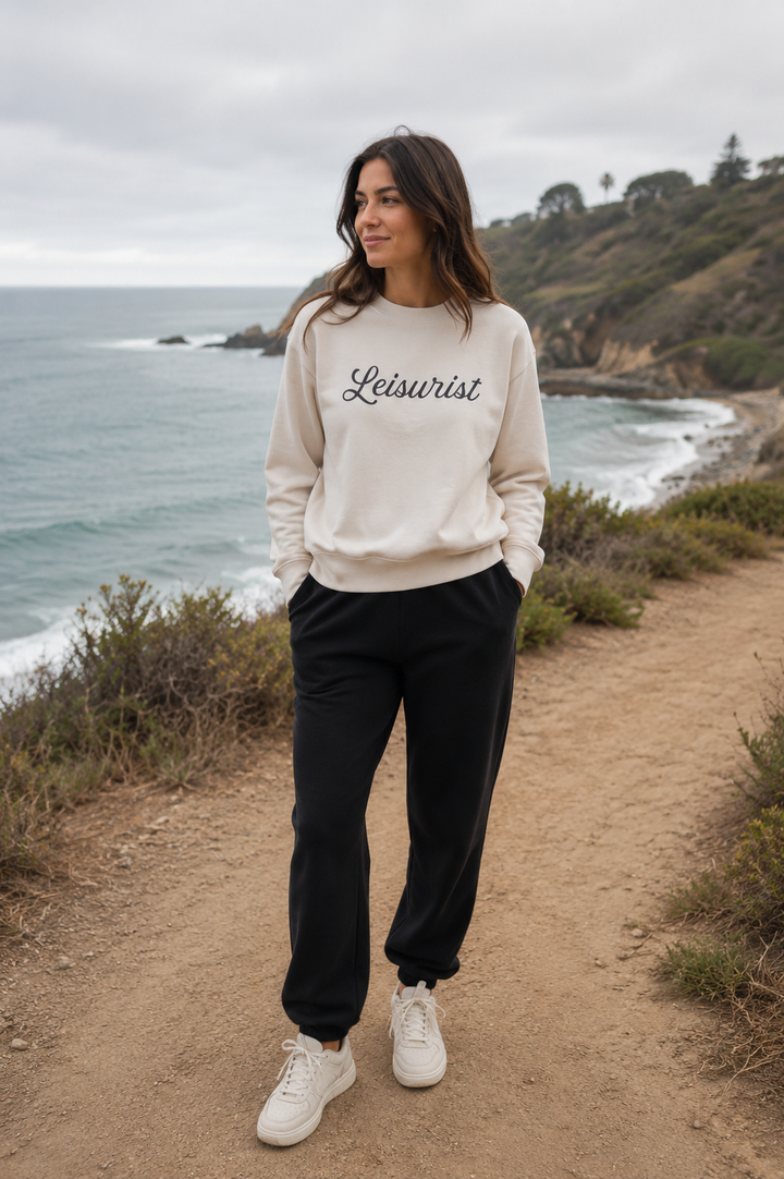 Woman wearing bone Leisurist script sweatshirt on beach trail 